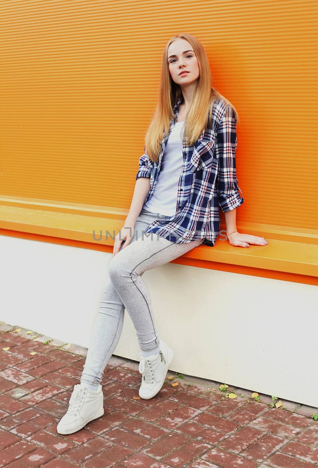 Fashion pretty woman in city over colorful orange background