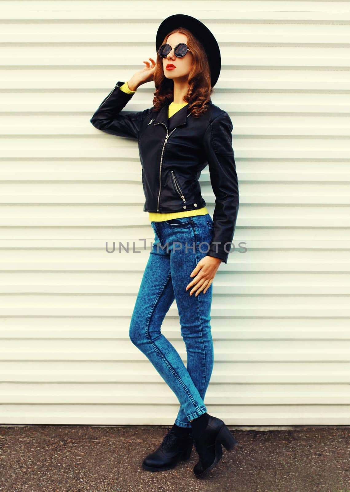 Fashionable stylish young woman model full length posing in black jacket, hat on white background