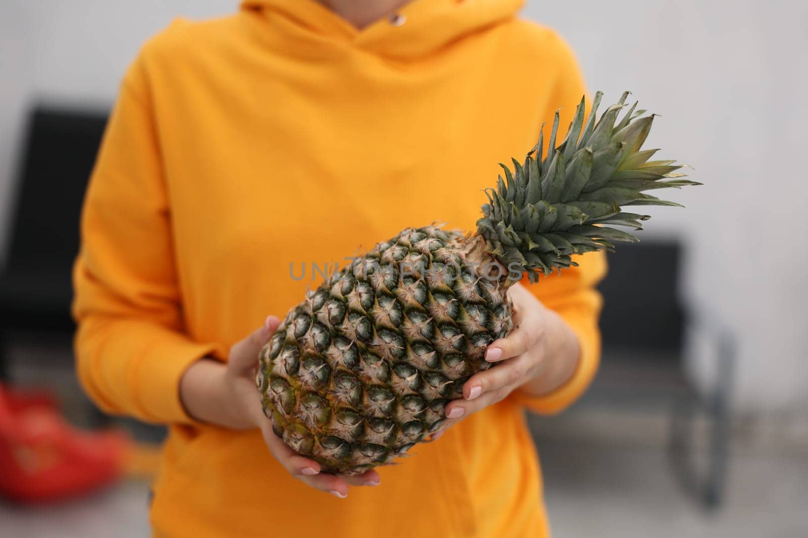 A person holding a ripe, juicy pineapple, proudly showcasing its vibrant colors and appealing health benefits