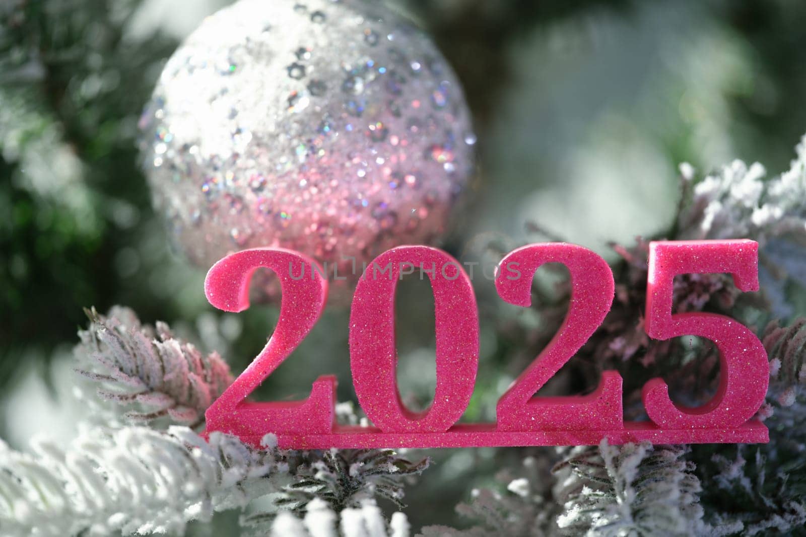 A vibrant 2025 decorative piece stands out beautifully among snowy Christmas ornaments, perfect for winter celebrations