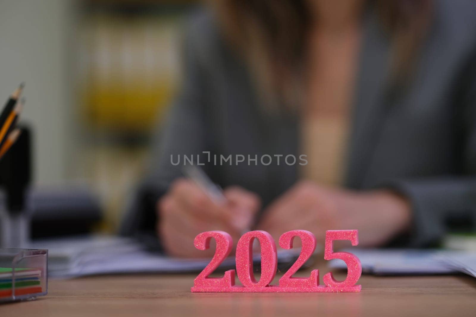 An ambitious professional meticulously planning for 2025, with vibrant figures displayed on their desk