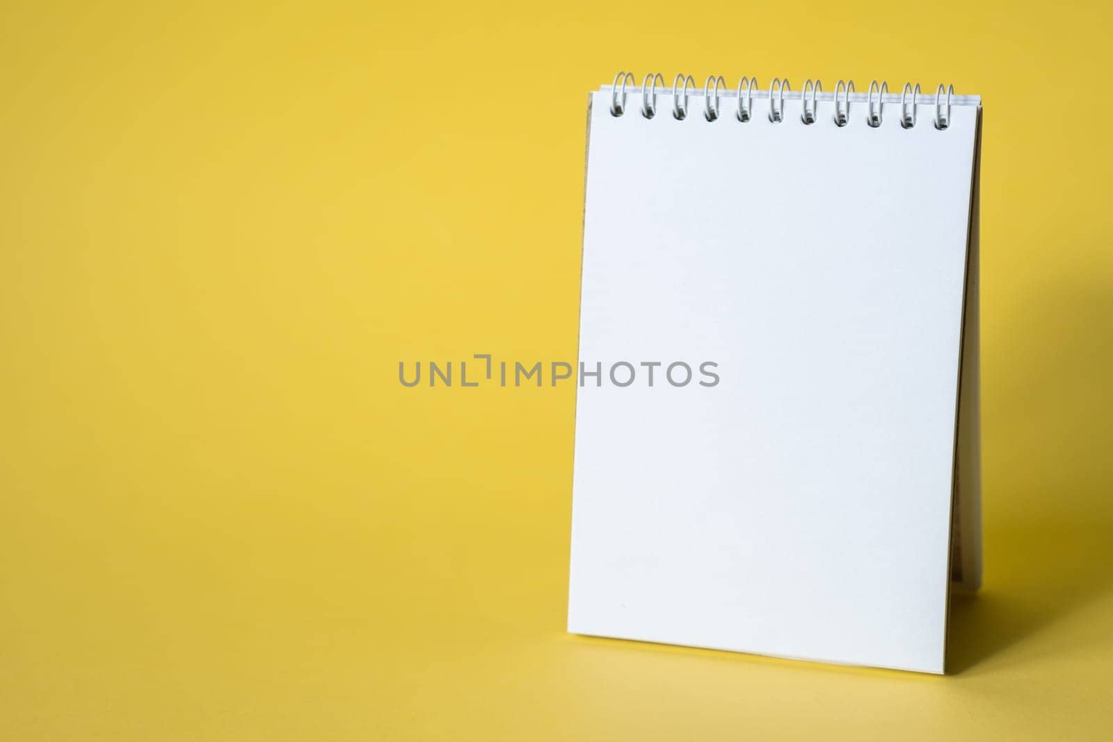 Opened notepad on a yellow background. Composition of writing to-dos for the day. The notebook lies on a plain background with space for writing.