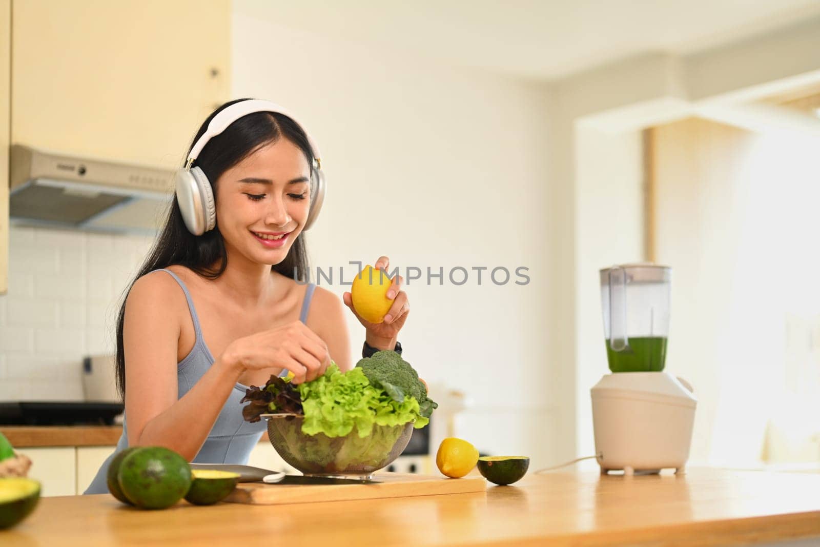 Beautiful woman preparing healthy vegan salad in the kitchen at home. Dieting and healthy lifestyle concept.