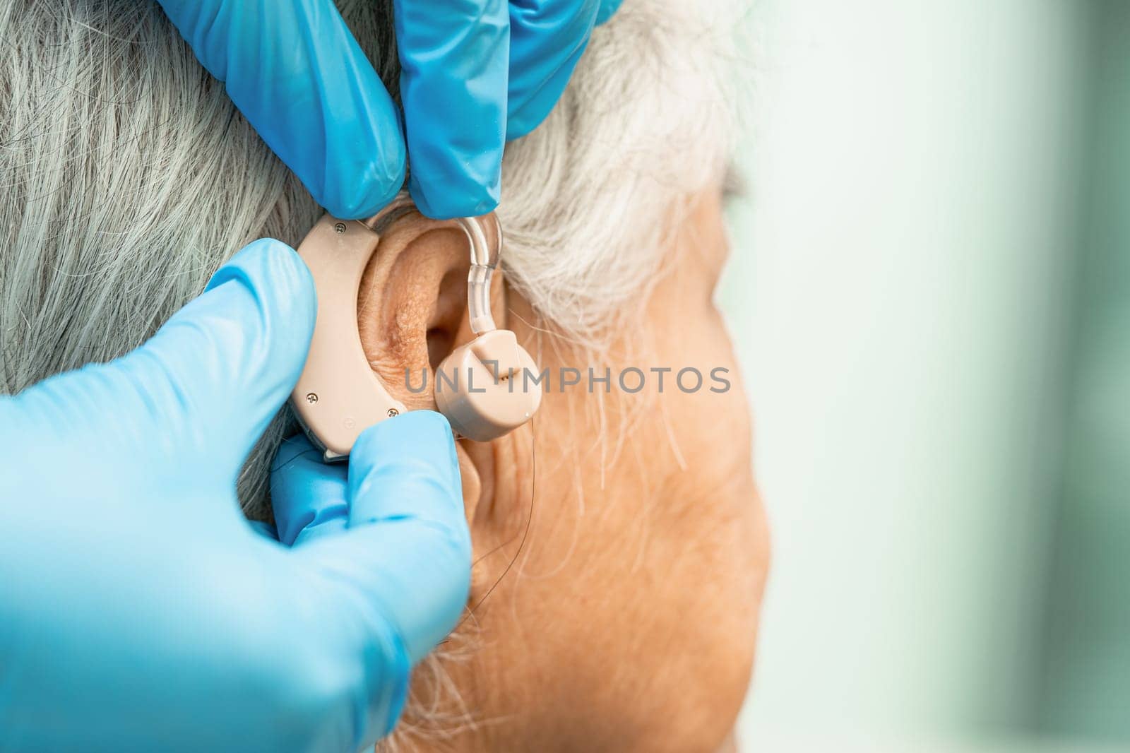 Asian senior woman patient wearing a hearing aid for treating hearing loss problem.