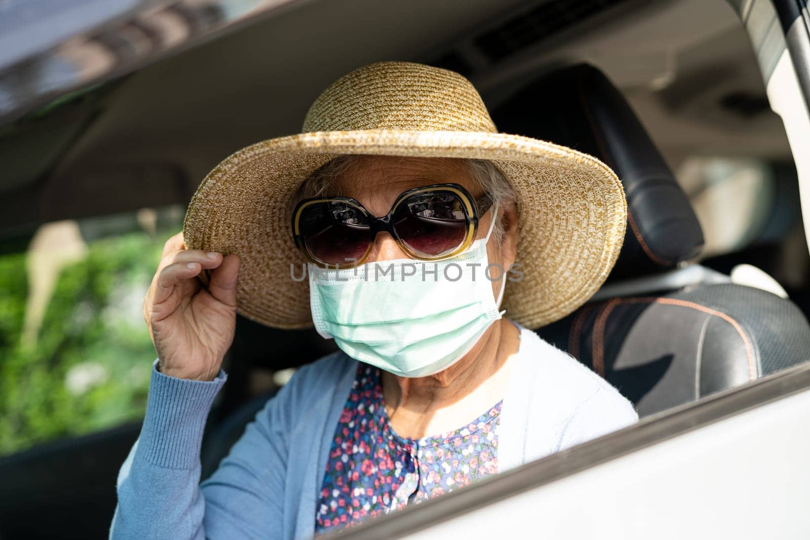 Asian elderly woman with hat sitting in car with enjoy and freedom in traveling trip. by pamai