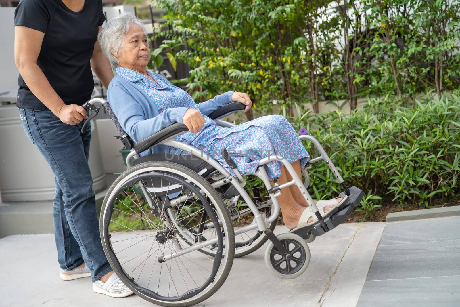 Caregiver help and care Asian senior woman patient sitting on wheelchair to ramp in nursing hospital, healthy strong medical concept. by pamai