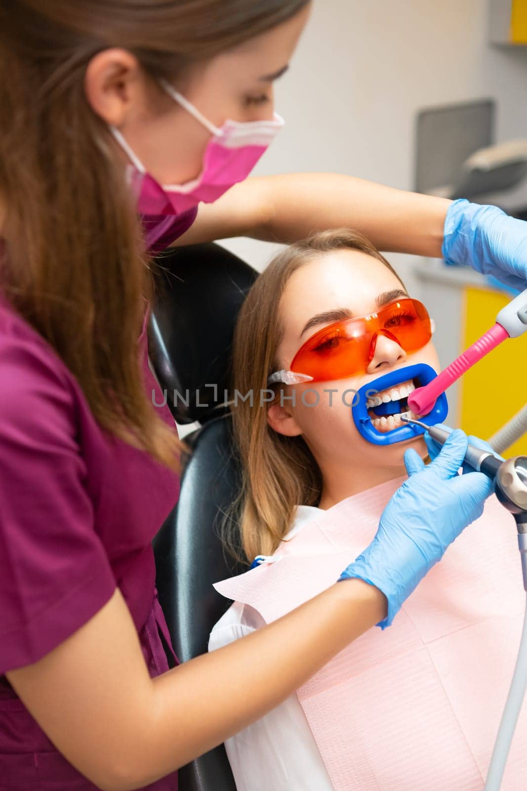 Dentist in gloves performing teeth cleaning from plaque detector on teeth. Doctor uses small tool with water supply in dental office