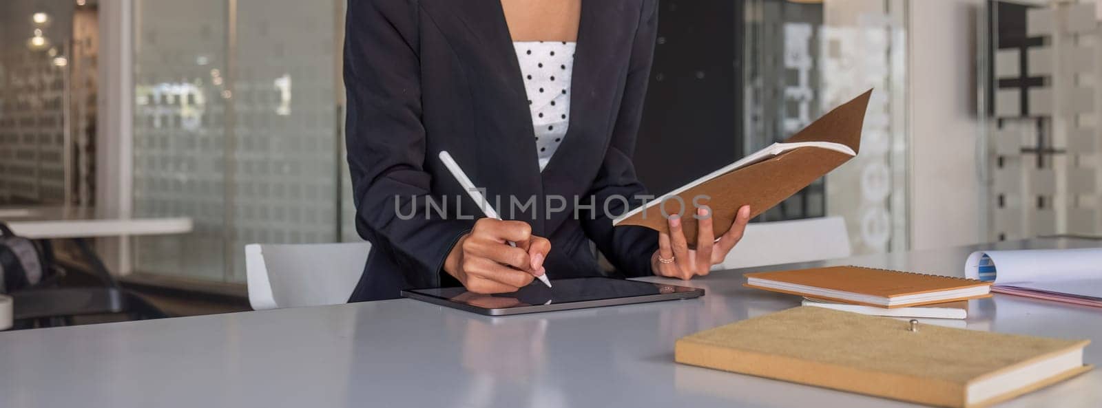 young Asian businesswoman taking notes using a laptop at the modern office. by wichayada