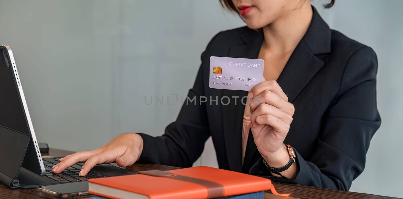 young Asian businesswoman enjoy shopping online using credit card at co-working.