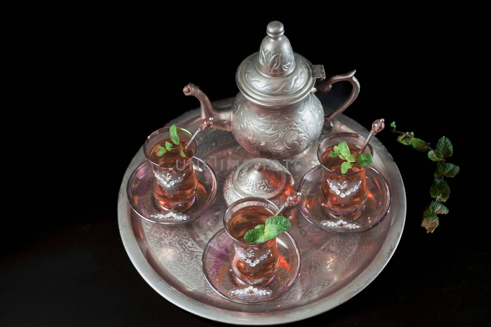 tray with Moorish tea with mint and silver pitcher and sugar bowl isolated on black background and copy space