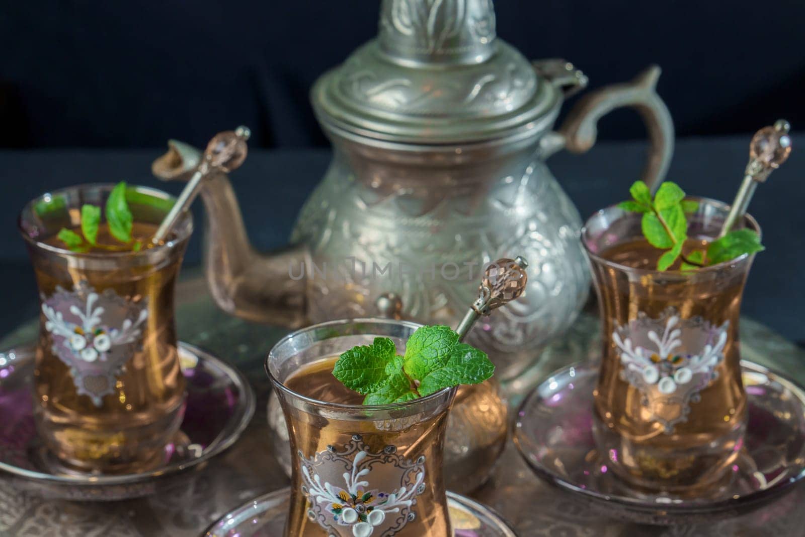 close-up of a traditional Moorish mint tea service, with decorated glassware and silver teapot and silver sugar bowl