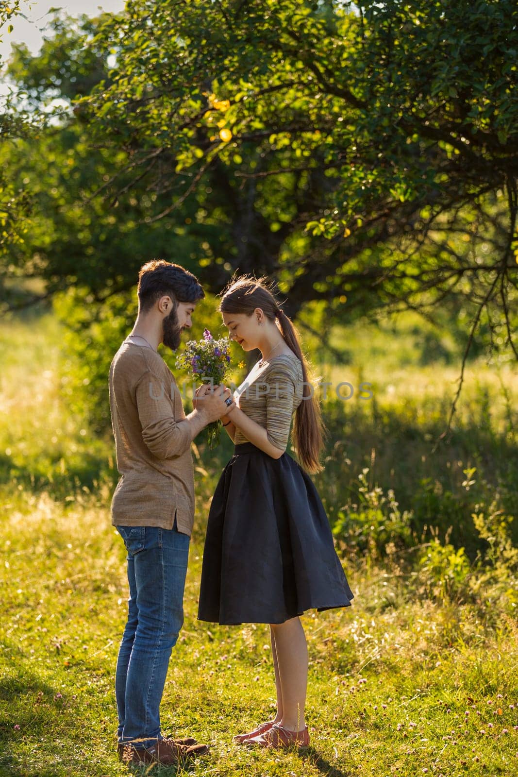 couple in nature with wildflowers, smelling a bouquet