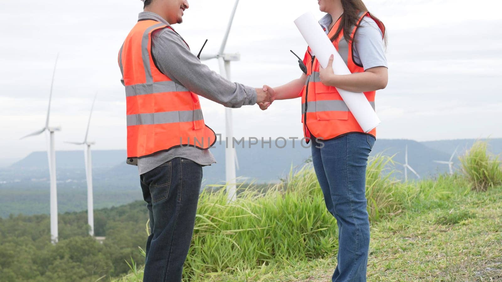 Male and female engineers working on a wind farm atop a hill or mountain in the rural. Progressive ideal for the future production of renewable, sustainable energy.