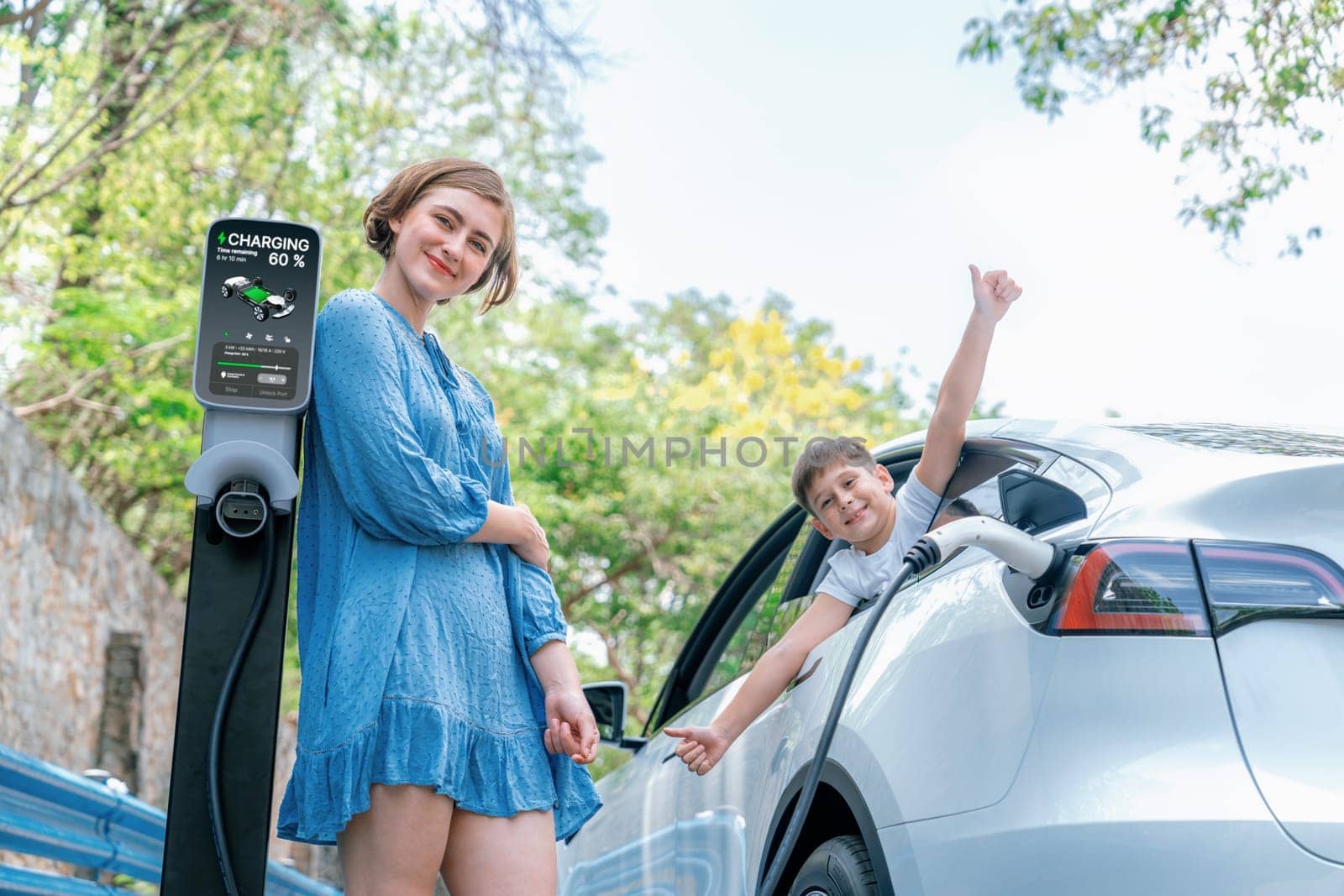 Family road trip vacation with electric vehicle, mother and son recharge EV car with green and clean energy. Nature and travel with eco-friendly car for sustainable environment. Perpetual