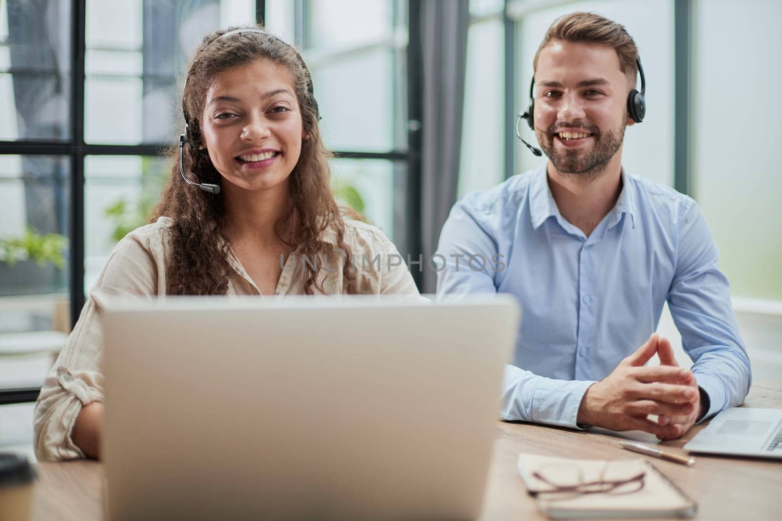 smilling man and charming woman are sitting at laptops in headphones by Prosto