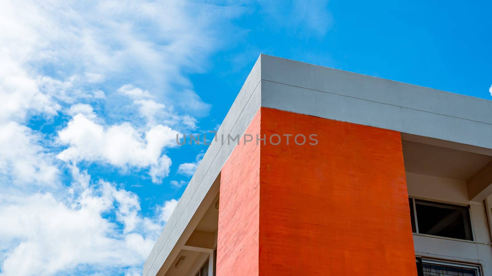 Orange building on a background of sky and white clouds.