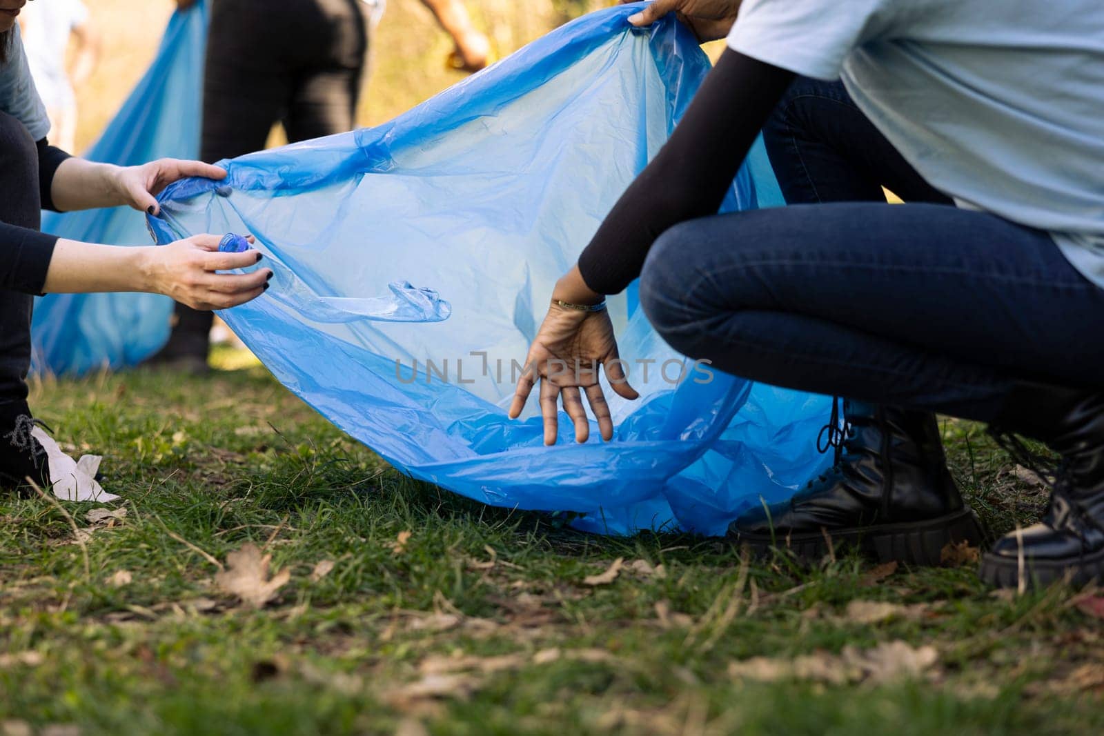 Motivated mother and child volunteering for litter cleanup in the woods, restoring natural ecosystem beauty and helping against pollution. Little kid recycling plastic waste in bags with her mom.