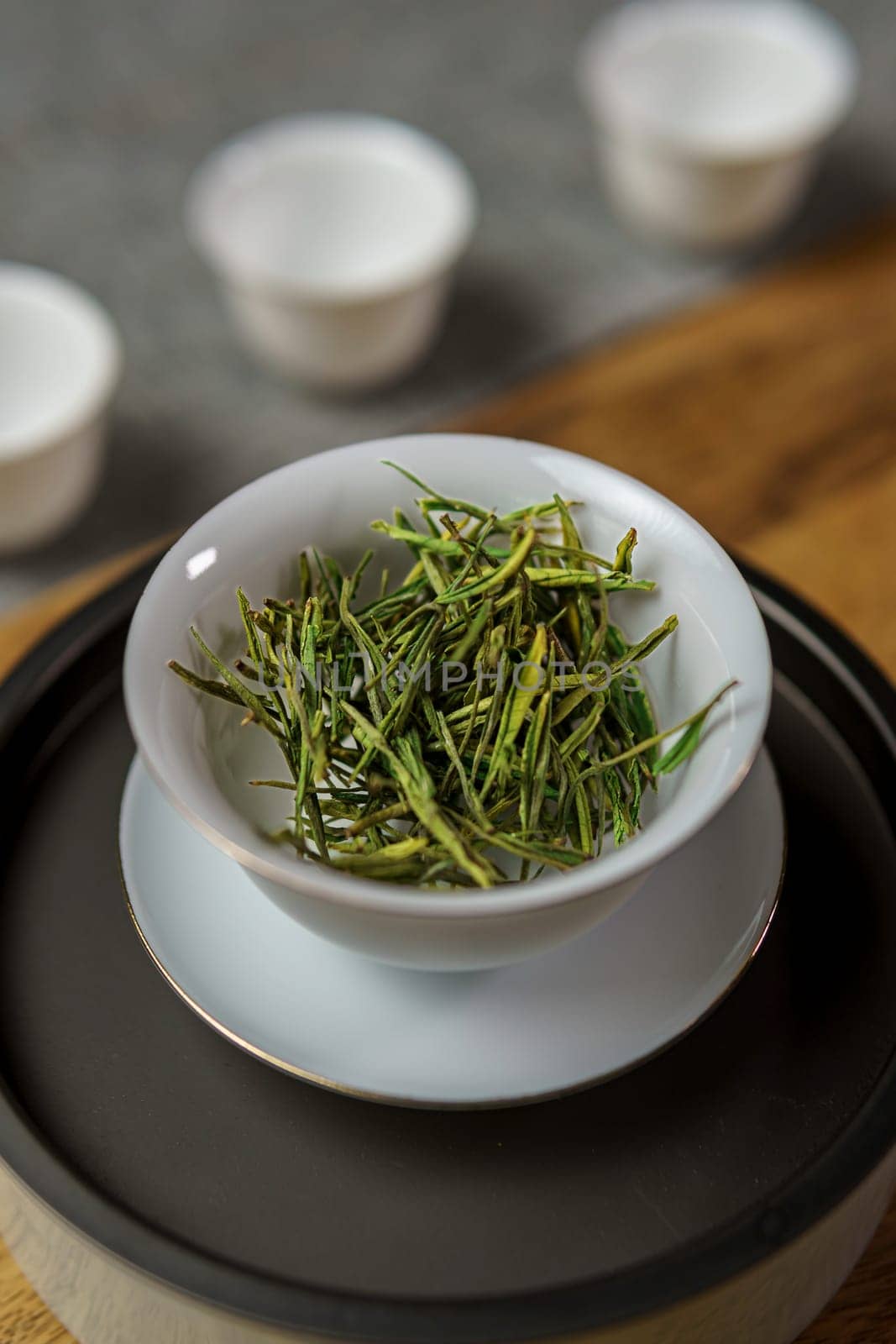 Delve into the captivating beauty of fresh, vibrant green tea leaves gracefully arranged in a traditional bowl
