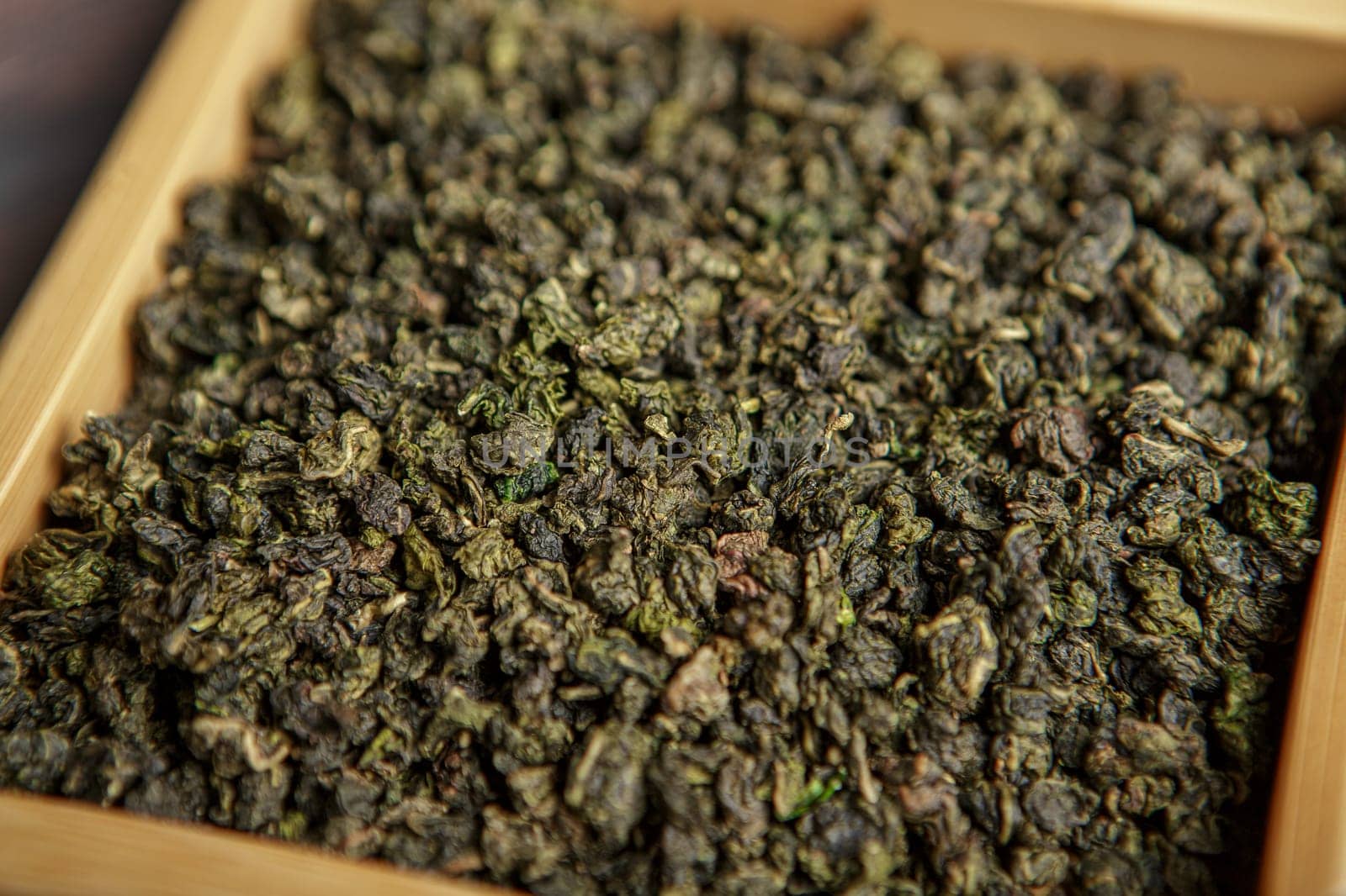 A closeup view of dried oolong tea leaves prominently displaying their vibrant green color and unique texture