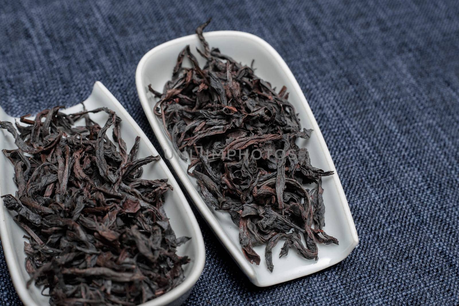 Highquality black tea leaves are elegantly presented in fine white dishes set against a richly textured background