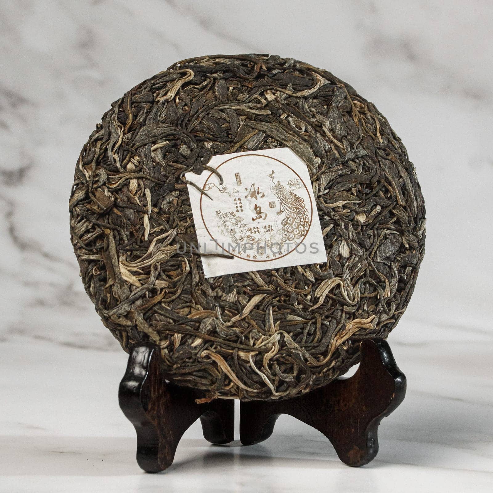 A beautifully stunning puerh tea cake that is artfully displayed and presented on a lovely wooden stand
