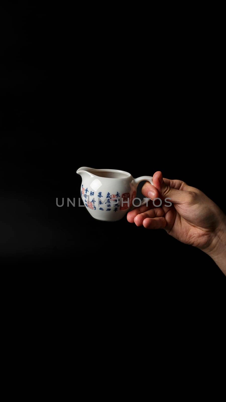 A graceful hand elegantly holds a vintage ceramic creamer, beautifully showcasing artistry in a minimalist style