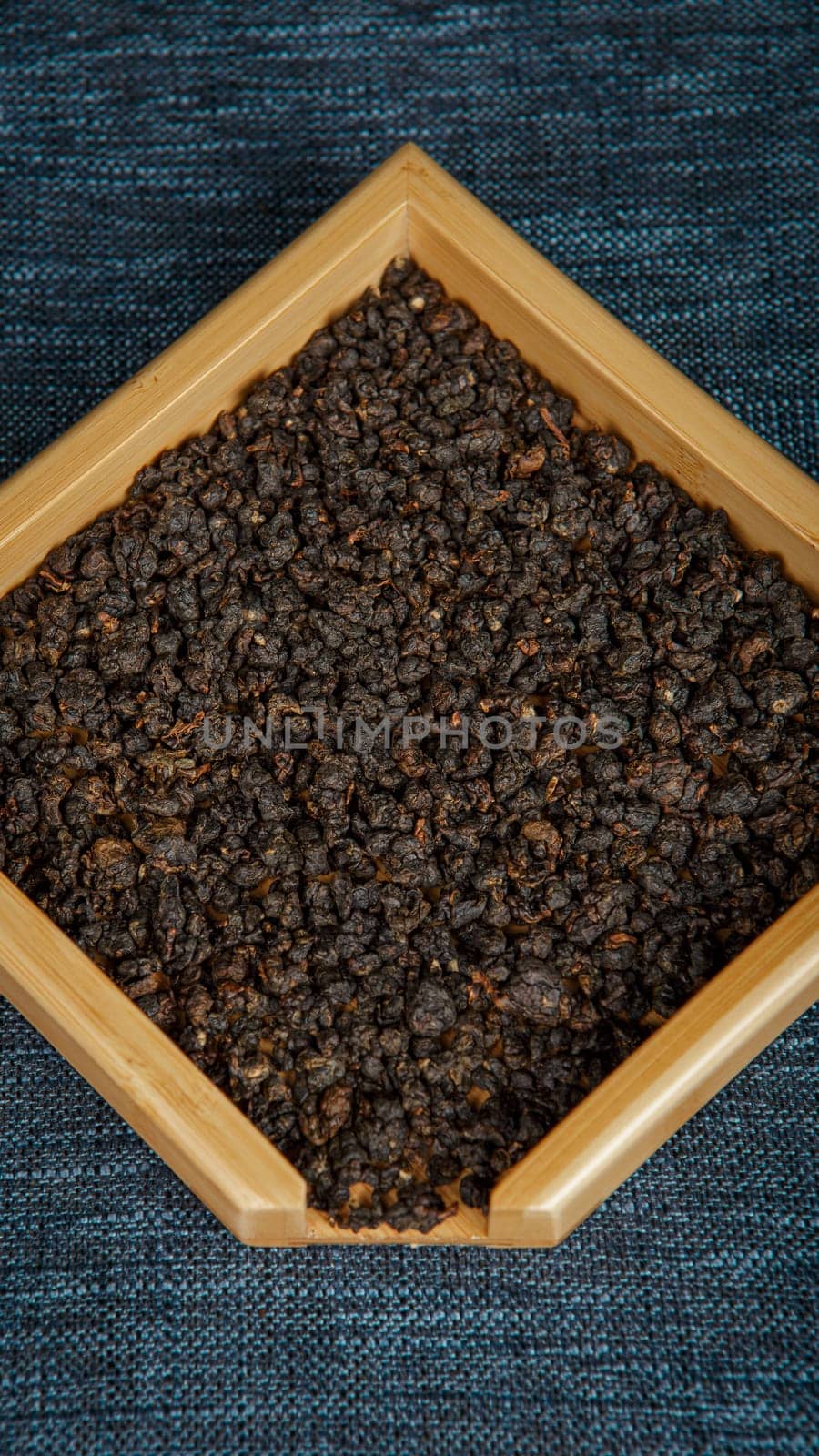 A closeup view of dark organic seeds delicately arranged in a rustic wooden tray placed on a textured surface