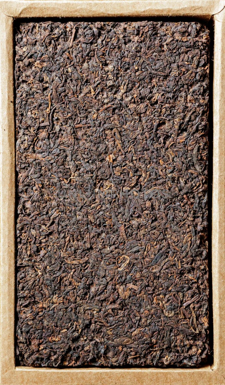 A closeup view of a dense black tea leaf cake, beautifully highlighting its rich texture and earthy tones
