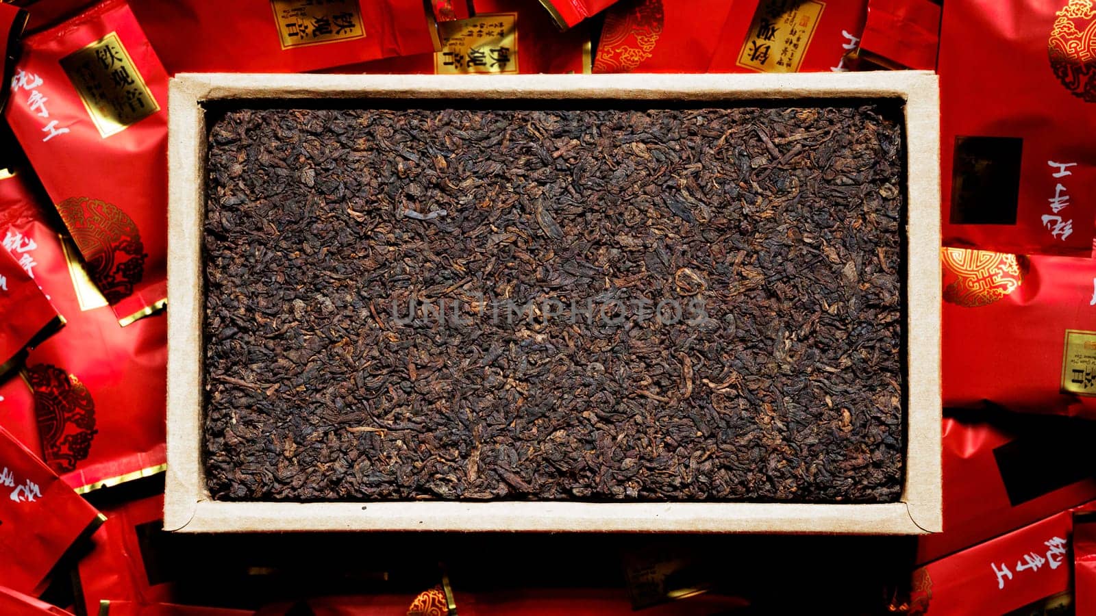An elegant display of loose leaf teas in a crafted wooden tray, with colorful, vibrant packaging around them