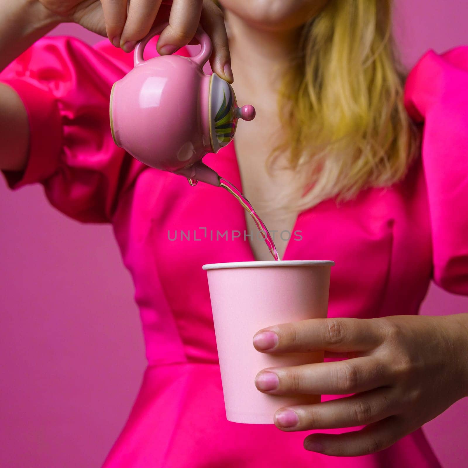 A stylish photo of a woman in a pink dress pouring tea into a cup, showcasing modern elegance and sophistication