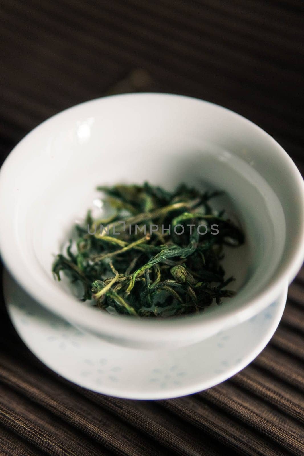 A soothing bowl of dried green tea leaves, beautifully prepared for brewing, showcasing its natural vibrancy