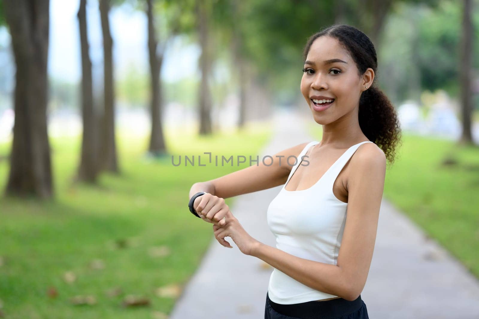 Cheerful African American woman pauses during her workout and checking her progress on her smartwatch.