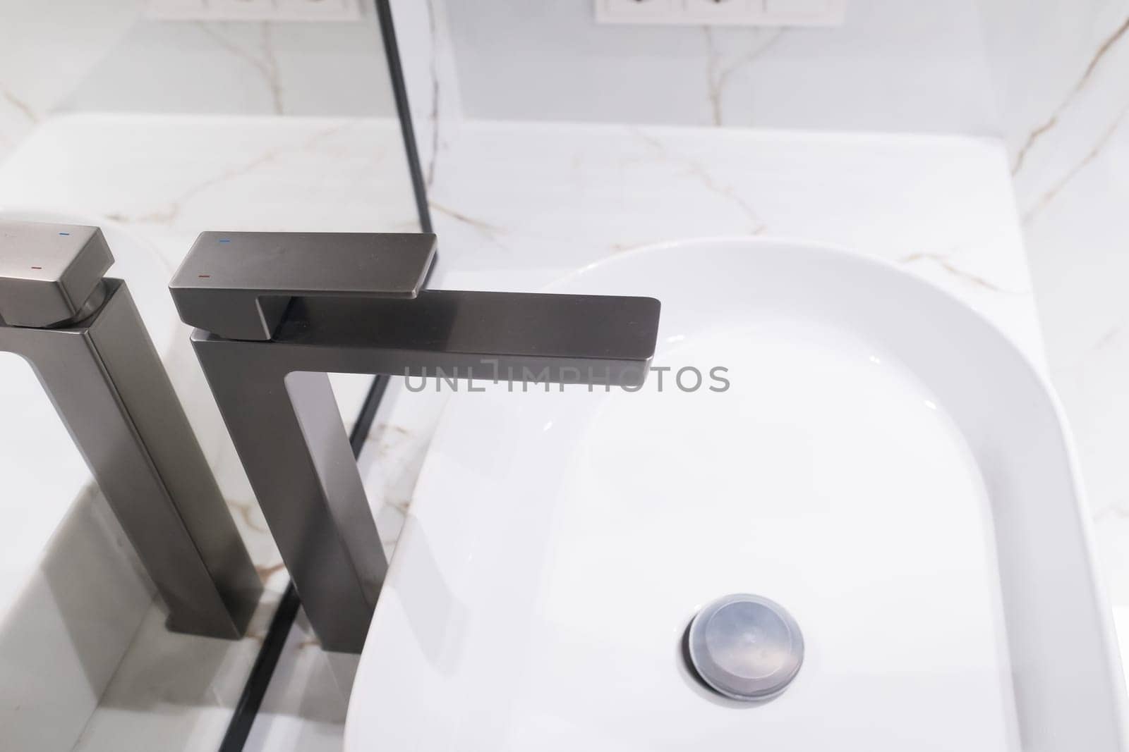 Stylish deluxe water faucet and white countertop sink in bathroom. Stylish bathroom.