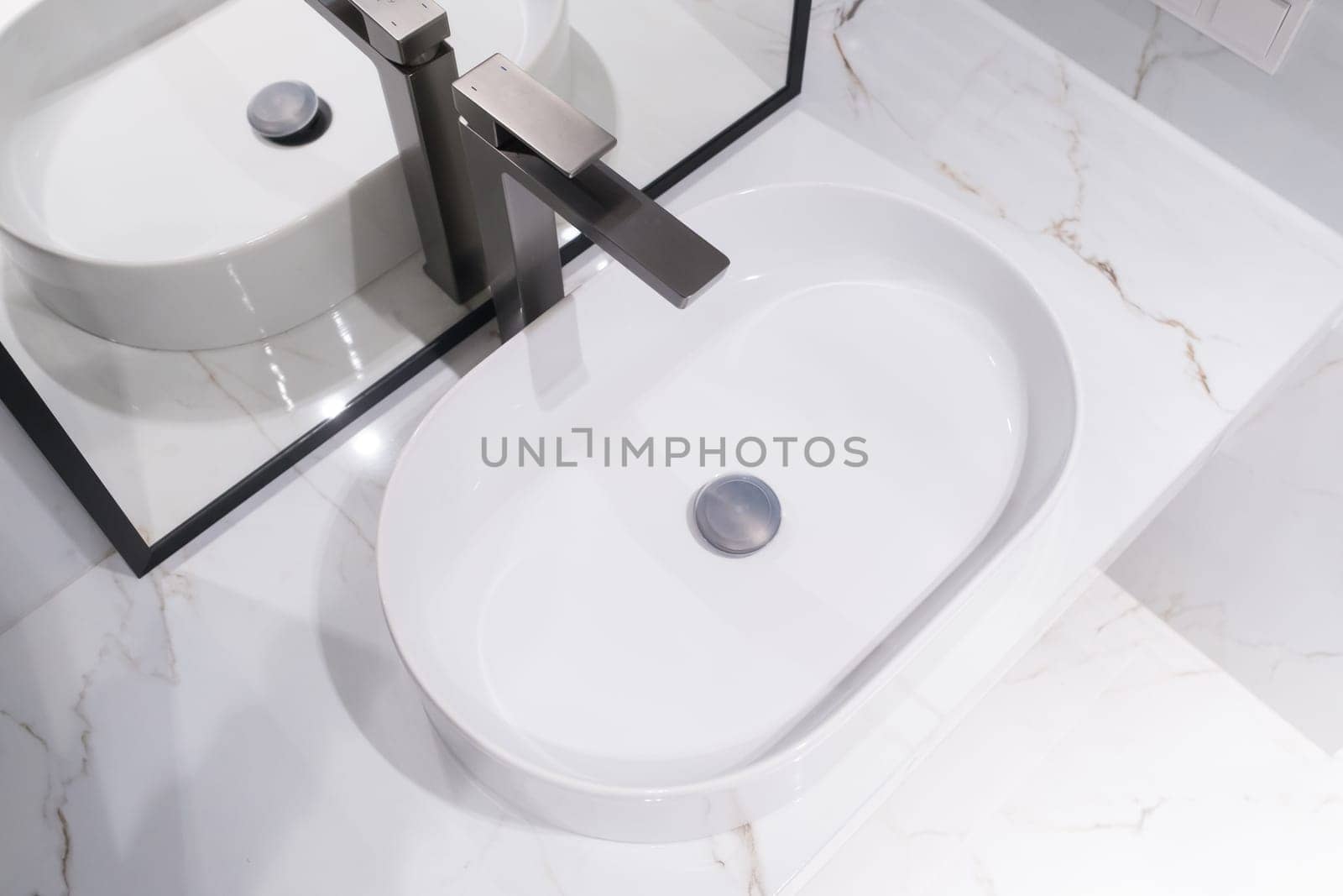 Chrome water faucet and white pedestal sink in bathroom . Stylish bathroom.