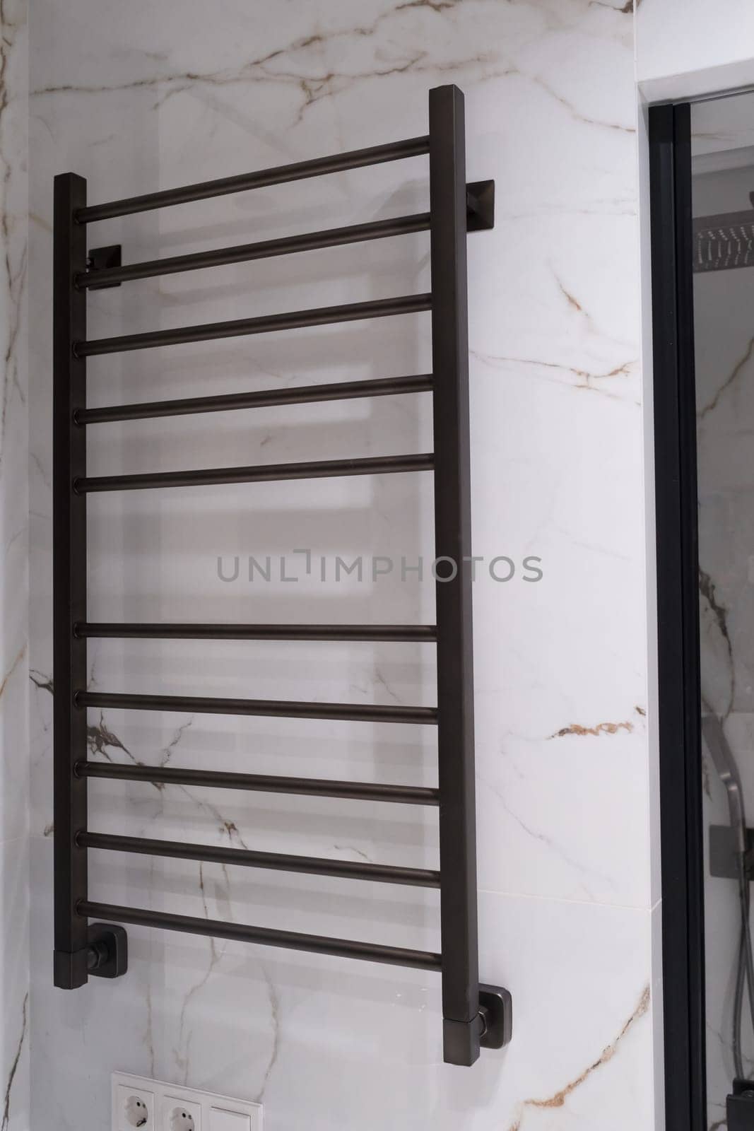 Modern black radiator on white marble wall in bathroom. New bathroom with granite white tiles.