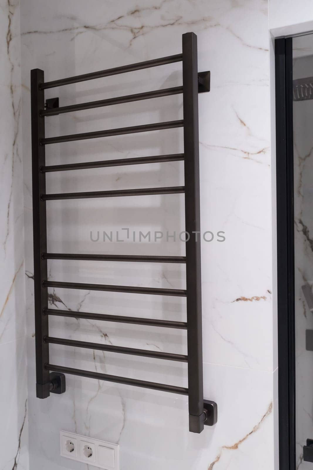Modern black radiator on white marble wall in bathroom. New bathroom with granite white tiles.