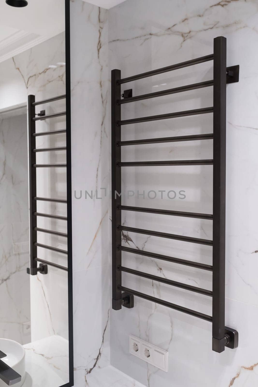 Modern black radiator on white marble wall in bathroom. New bathroom with granite white tiles.