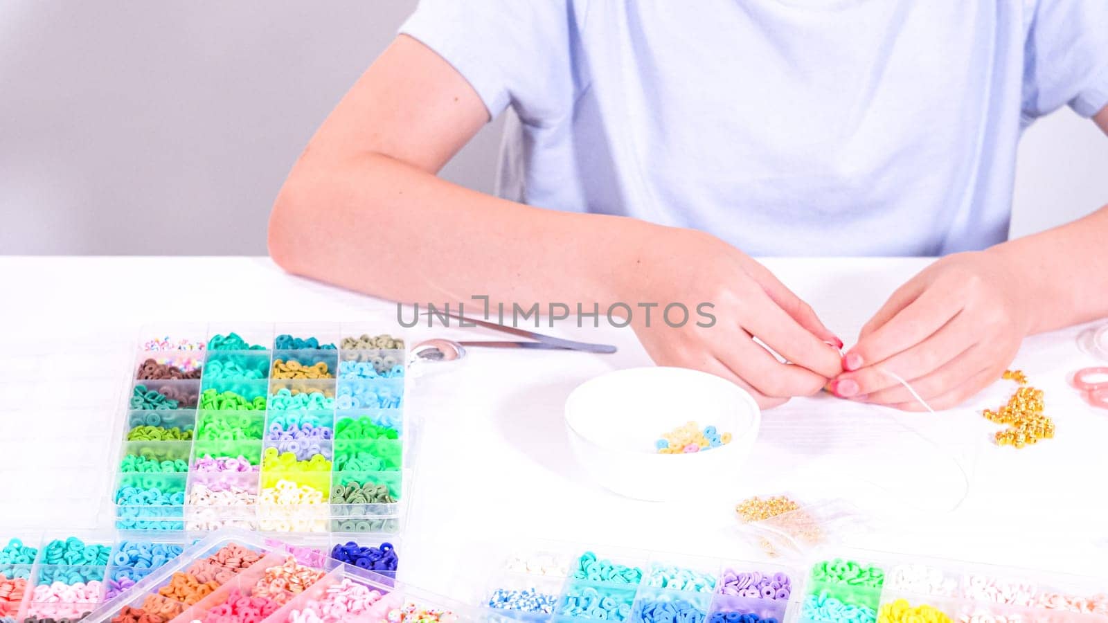 Delicate fingers of a young girl navigate through a treasure trove of bright, multicolored beads, each compartment revealing a new hue to choose from.
