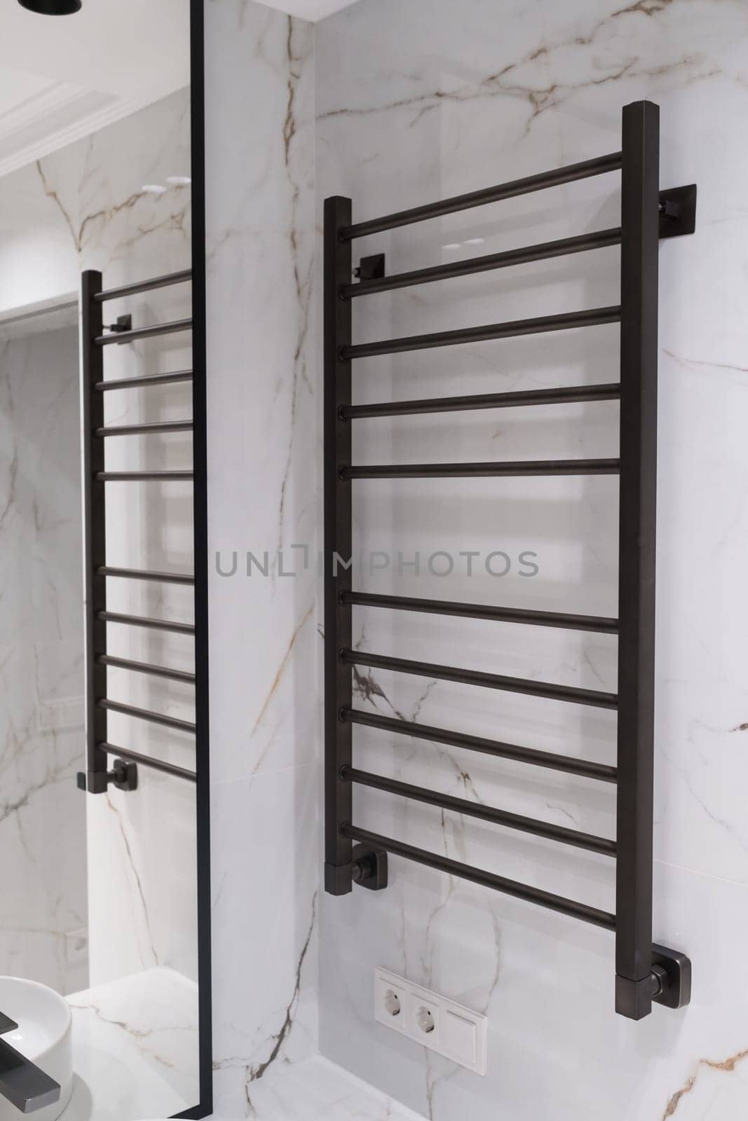 Modern black radiator on white marble wall in bathroom. New bathroom with granite white tiles.