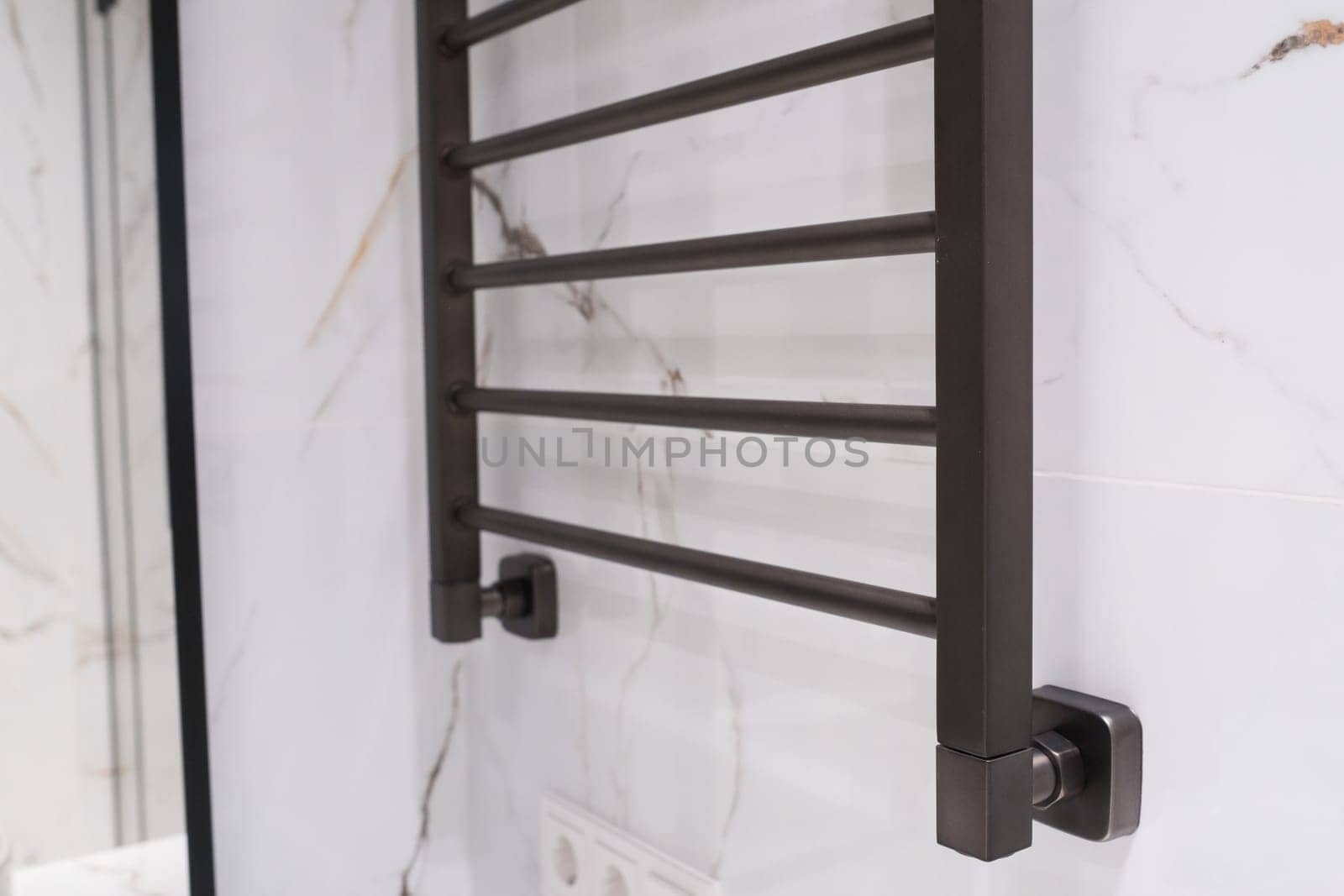 Modern black radiator on white marble wall in bathroom. New bathroom with granite white tiles.