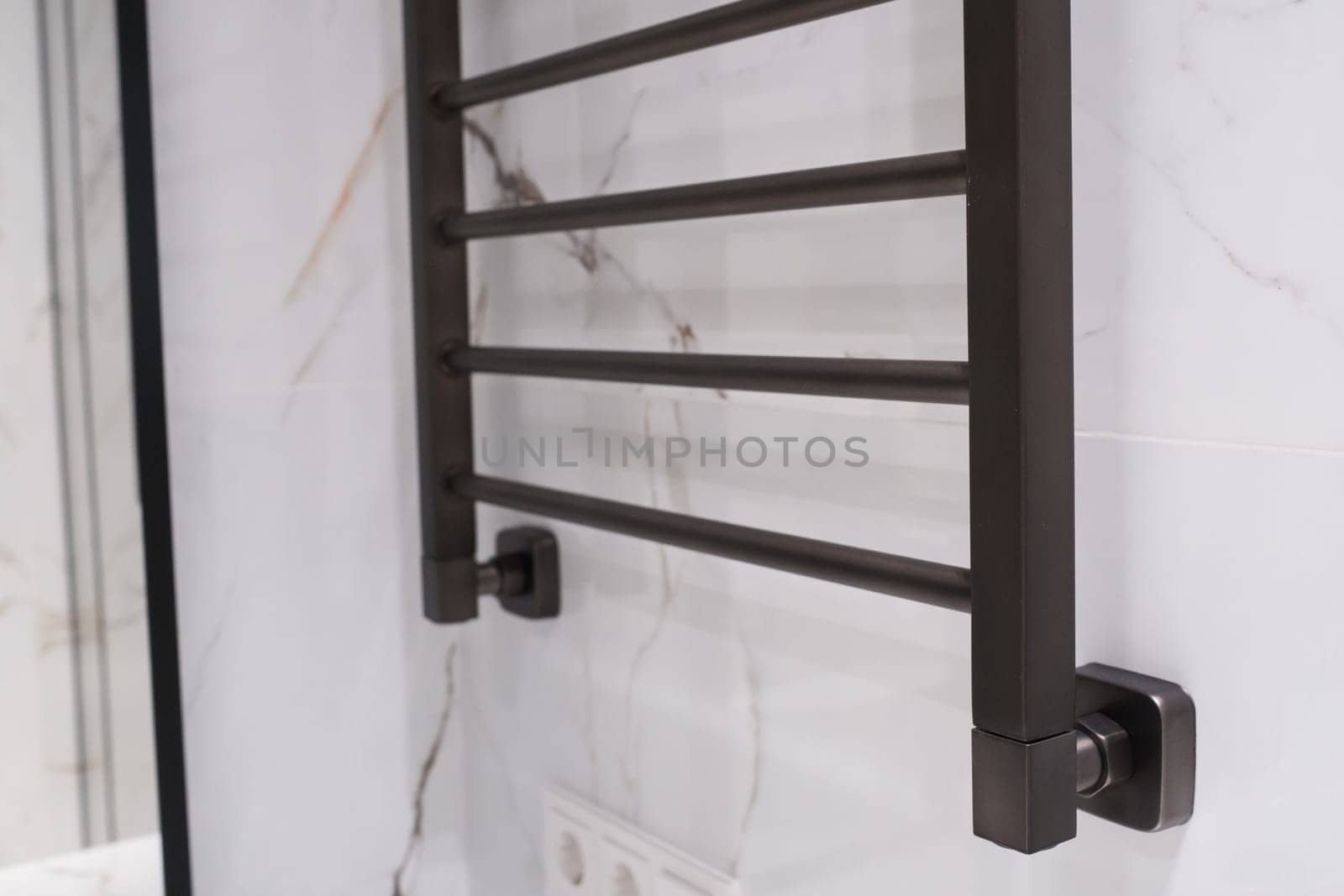 Modern black radiator on white marble wall in bathroom. New bathroom with granite white tiles.