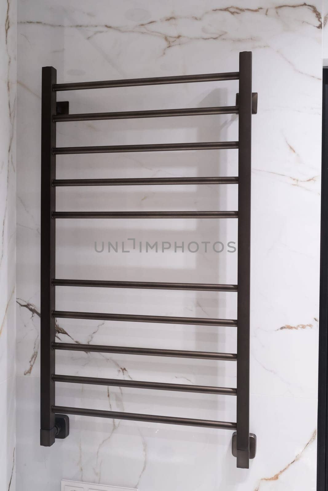 Modern black radiator on white marble wall in bathroom. New bathroom with granite white tiles.