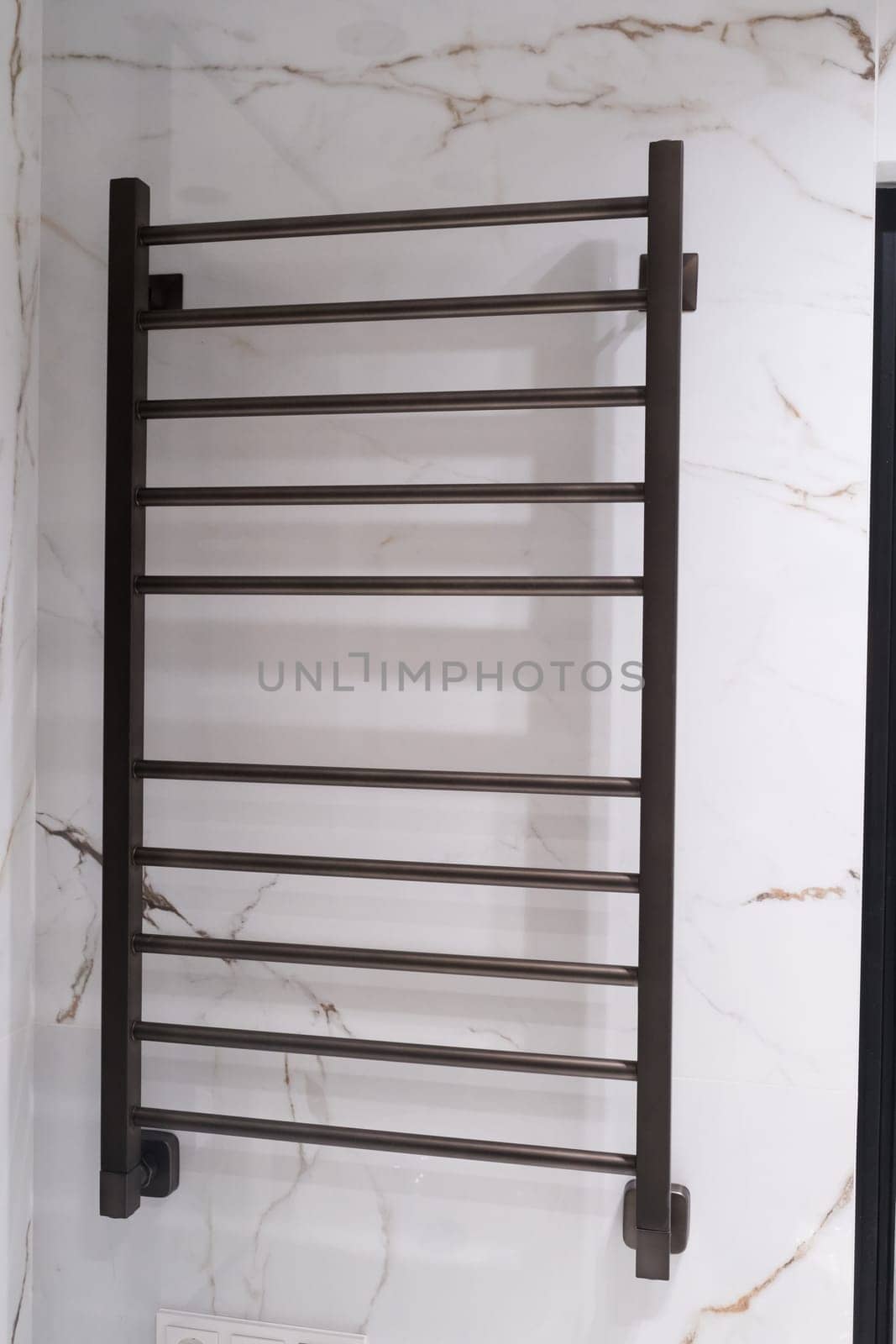 Modern black radiator on white marble wall in bathroom. New bathroom with granite white tiles.