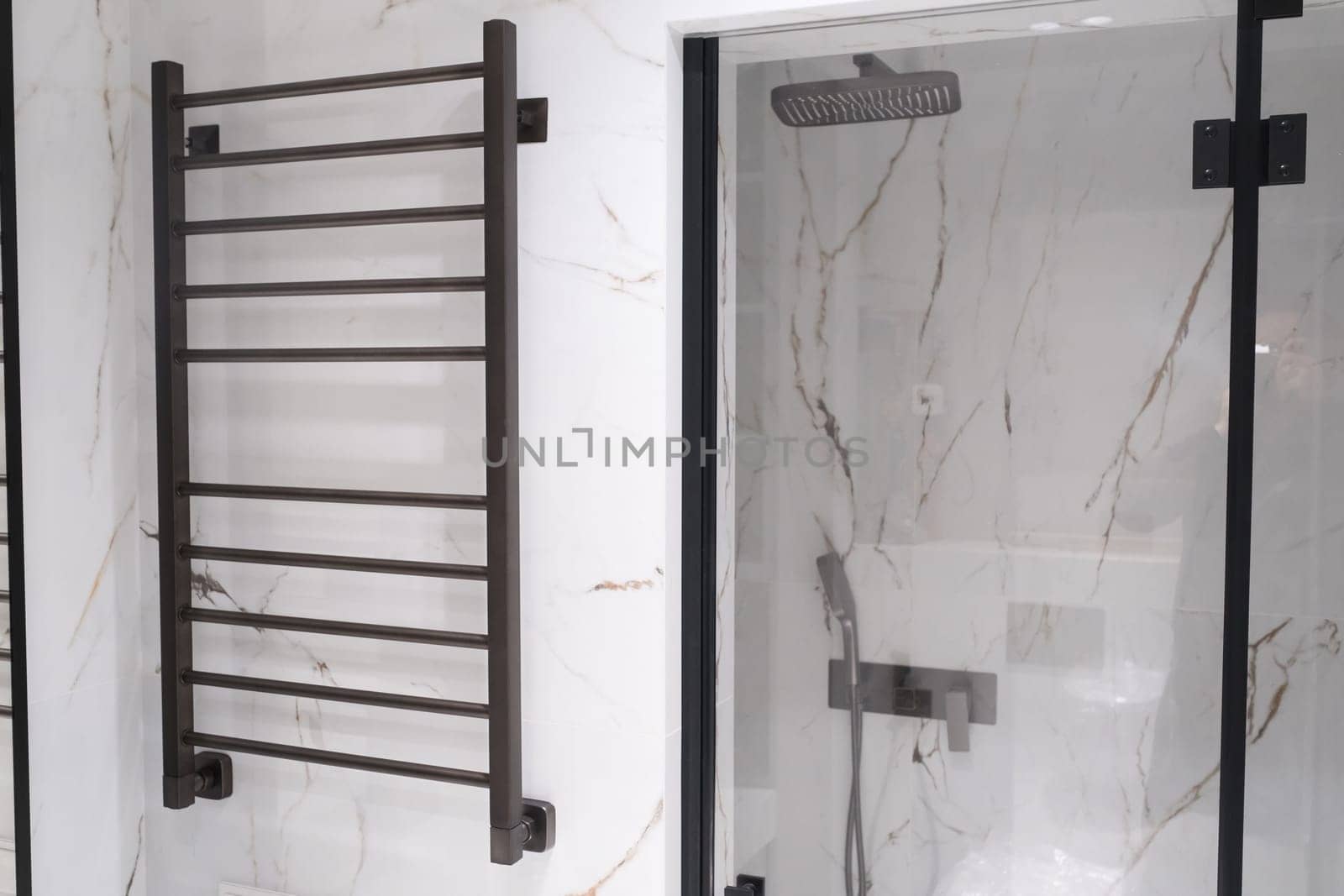 Modern black radiator on white marble wall in bathroom. New bathroom with granite white tiles.