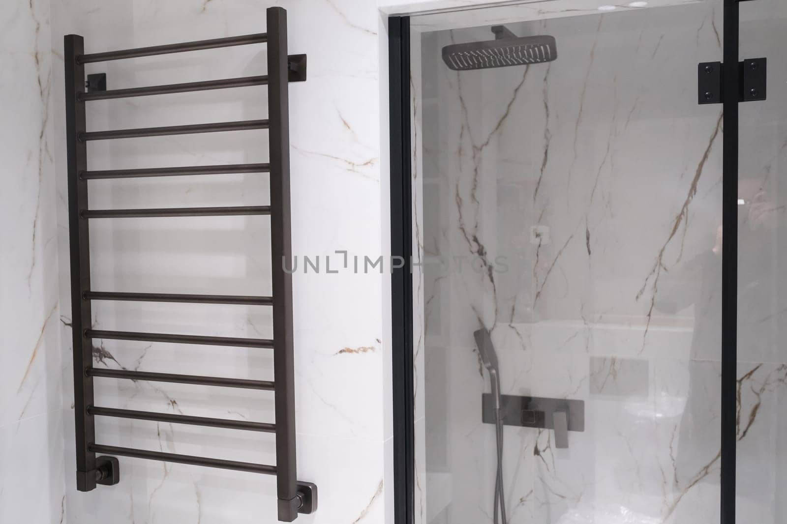 Modern black radiator on white marble wall in bathroom. New bathroom with granite white tiles.