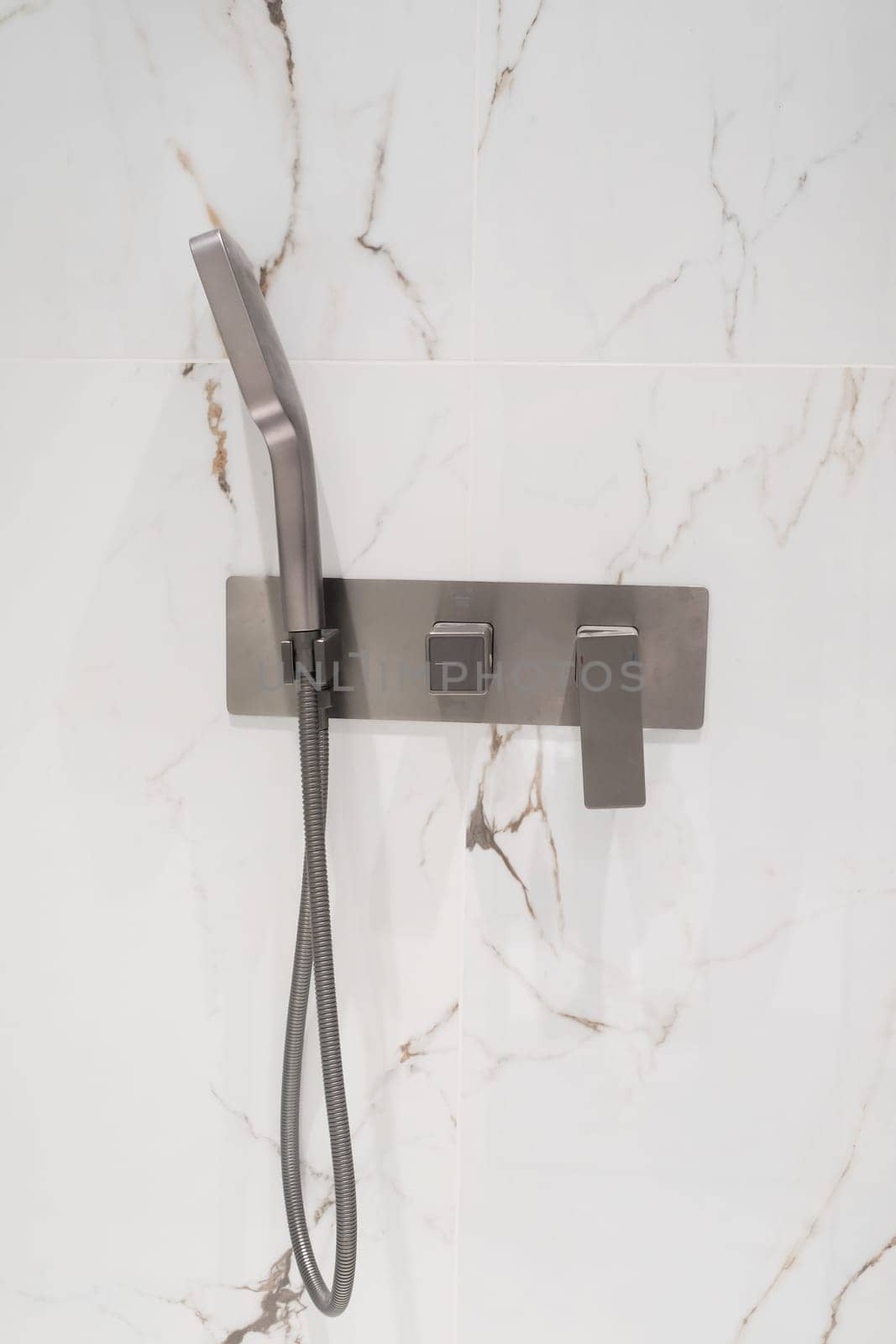 Luxury chrome faucet and shower in shower stall with white marble walls. Modern luxury shower cubicle.