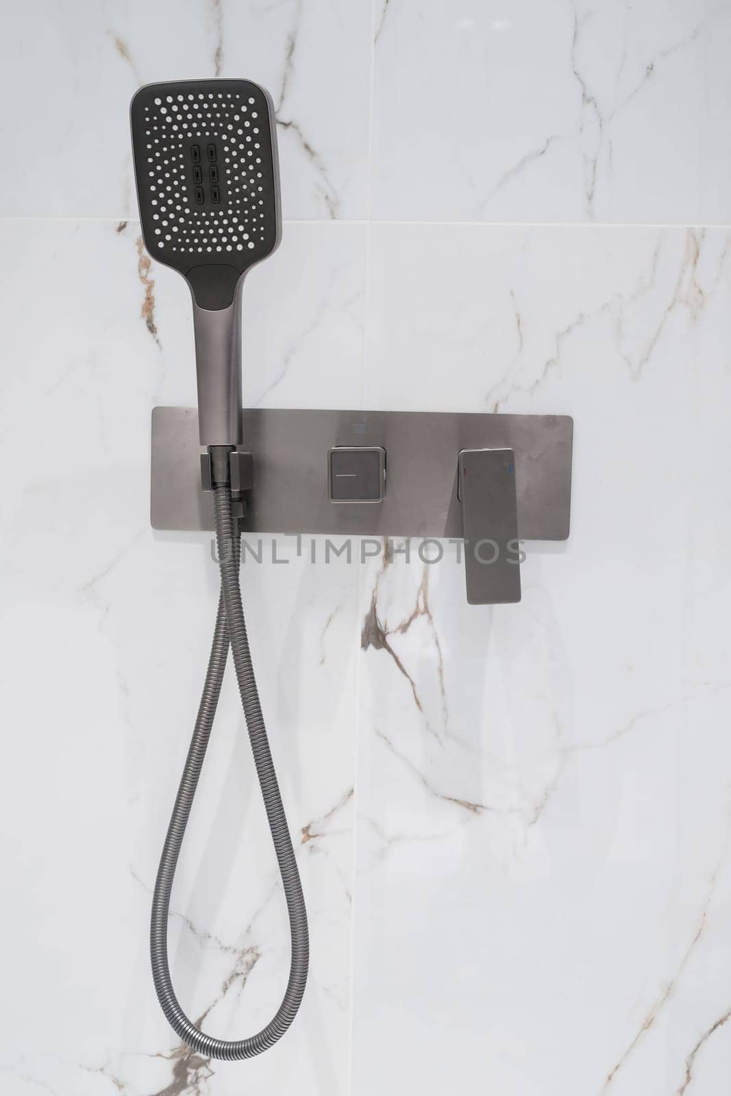 New stylish faucet and shower in shower enclosure with white granite walls. Modern luxury shower cubicle.