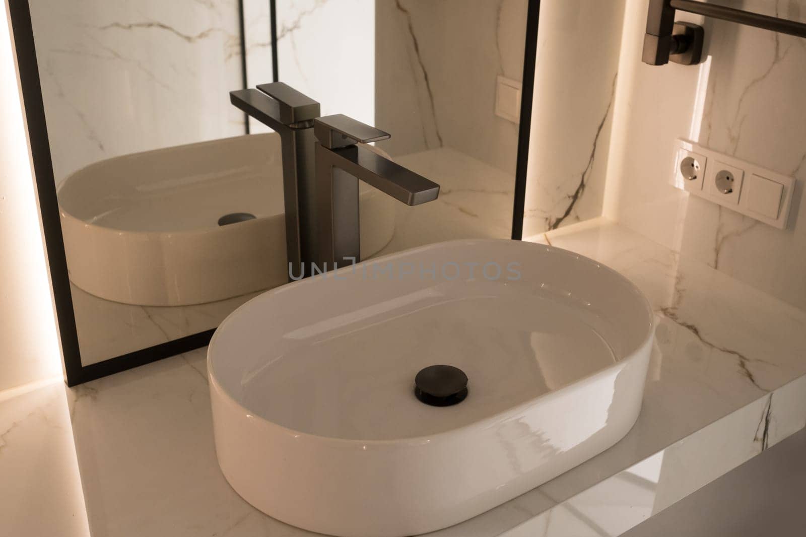 Chrome water faucet and white pedestal sink in bathroom . Stylish bathroom.