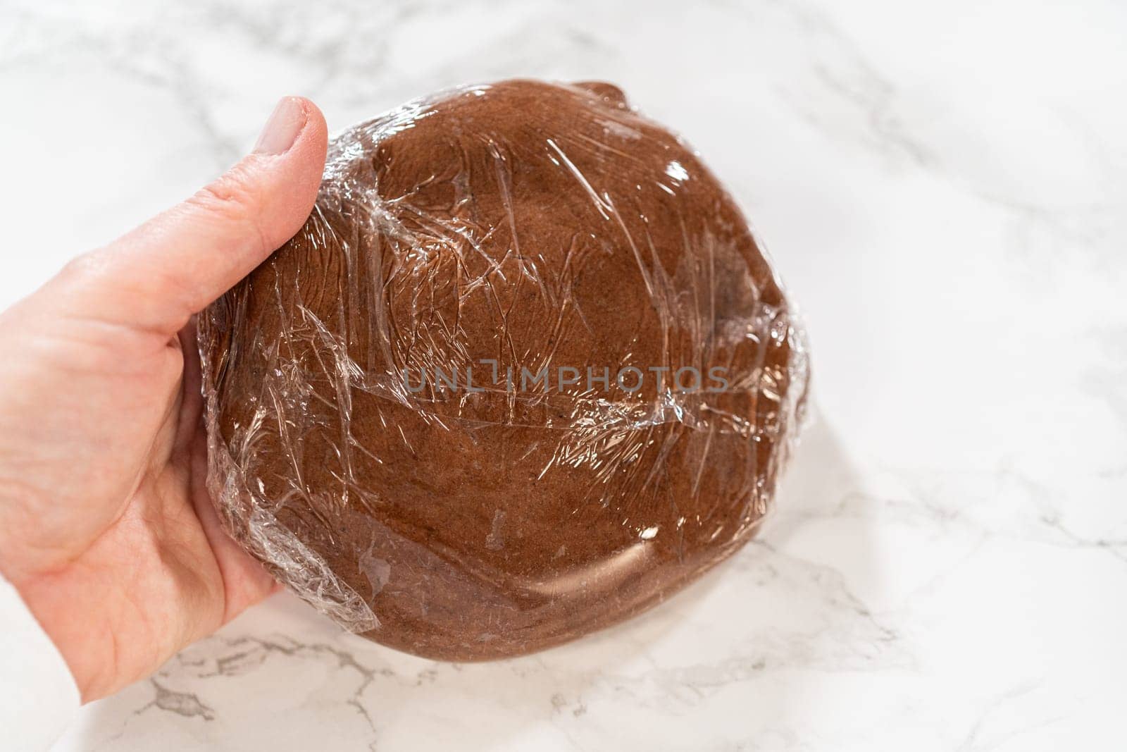 Stacked discs of Chocolate Ginger Sugar Cookie Dough wrapped in plastic, ready to chill, showing a smooth and uniform dough texture.