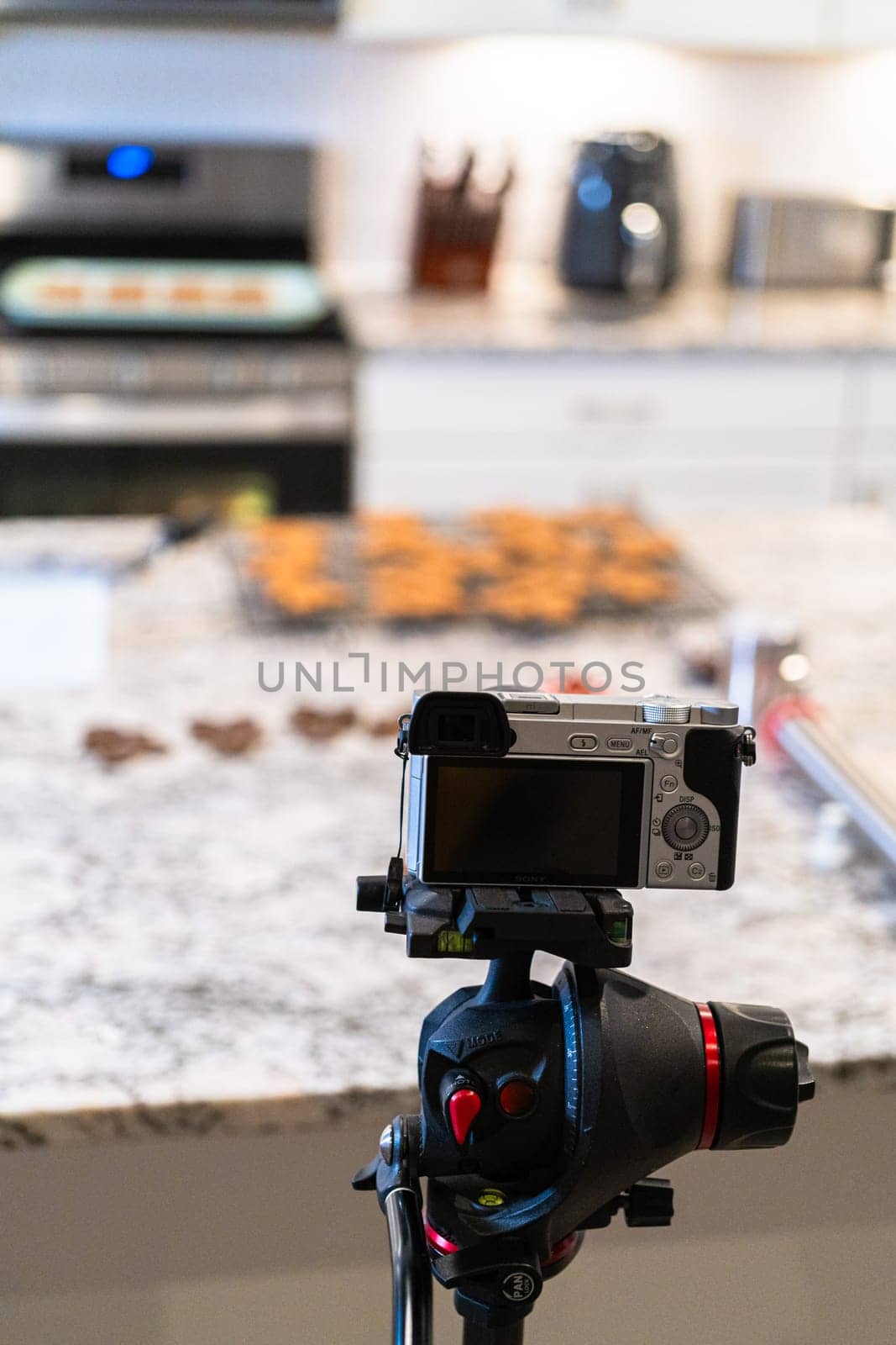 A DSLR camera, set up in a sleek, modern kitchen, captures the making of a video recipe for vlogging.